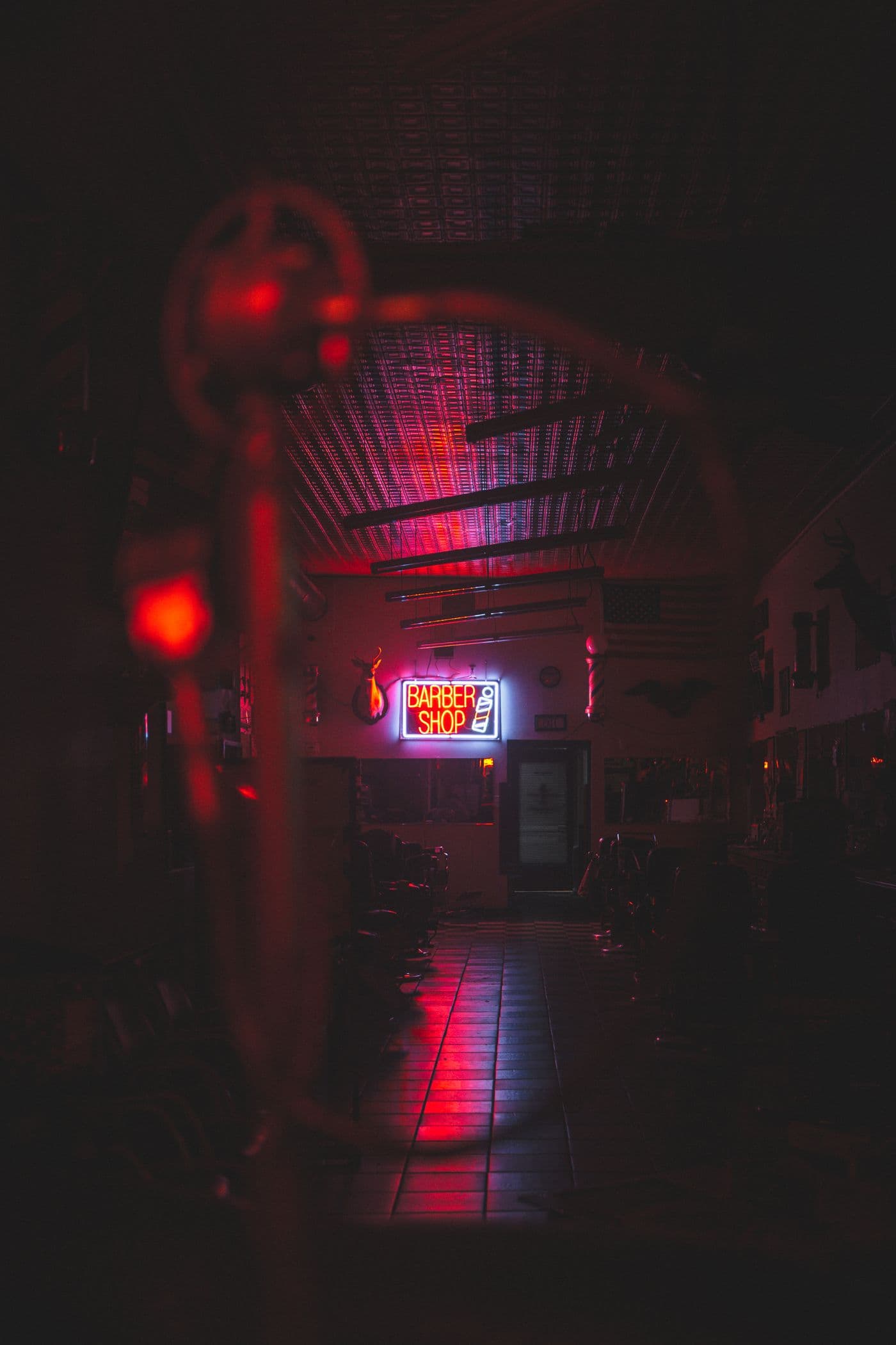 Una barbería vacía de noche, con el letrero de neón de Barber Shop encendido al fondo.