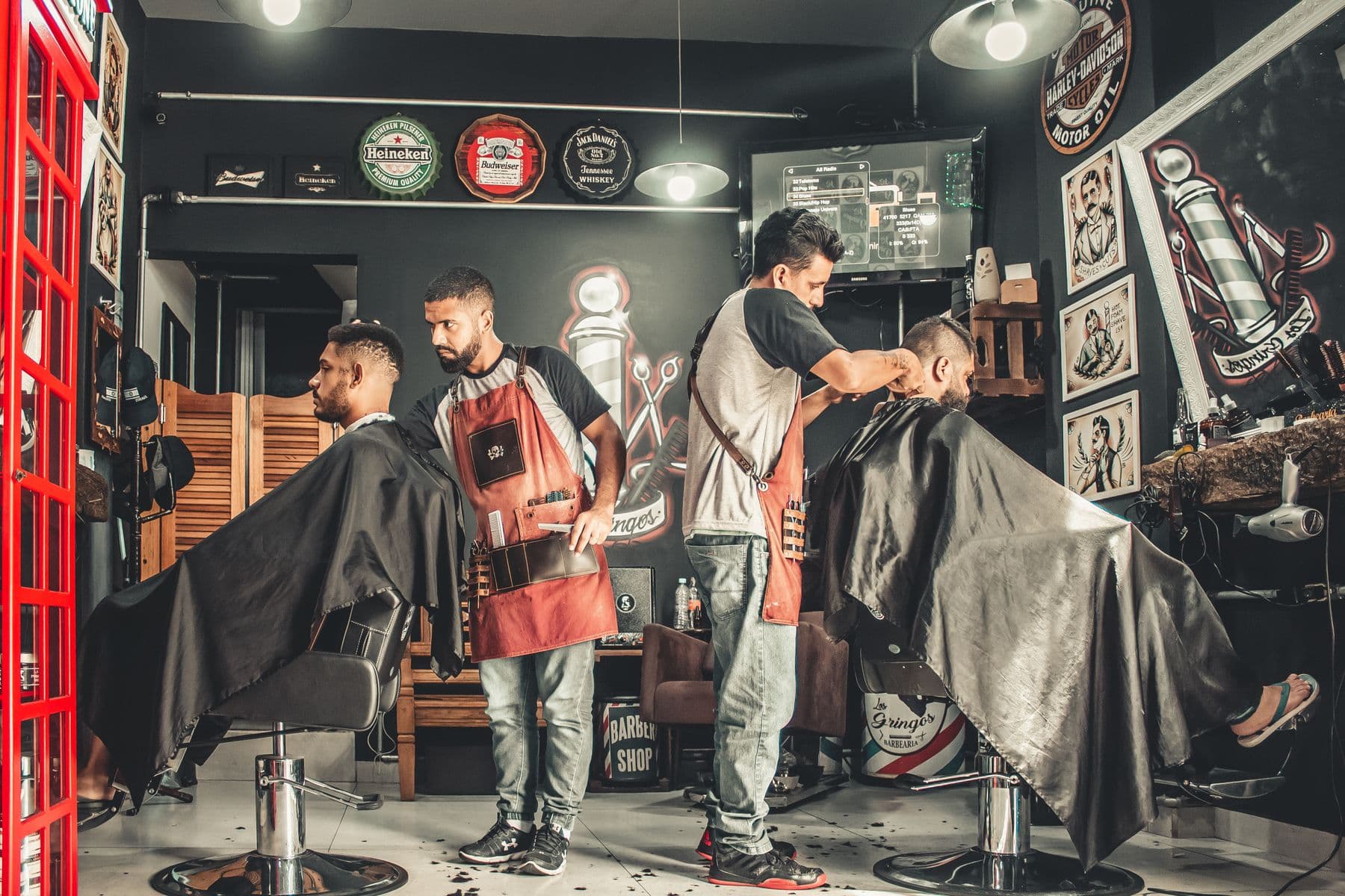 Una barbería con tres barberos atendiendo a sus clientes al mismo tiempo.