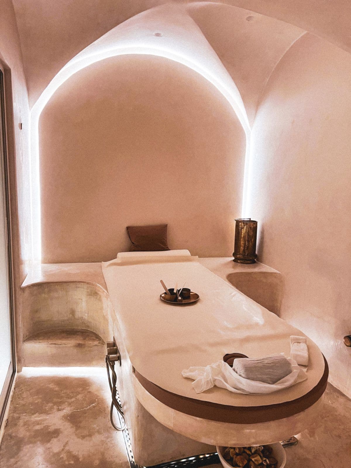 Una cabina de masajes minimalista, en tonos arena y con luz cálida.