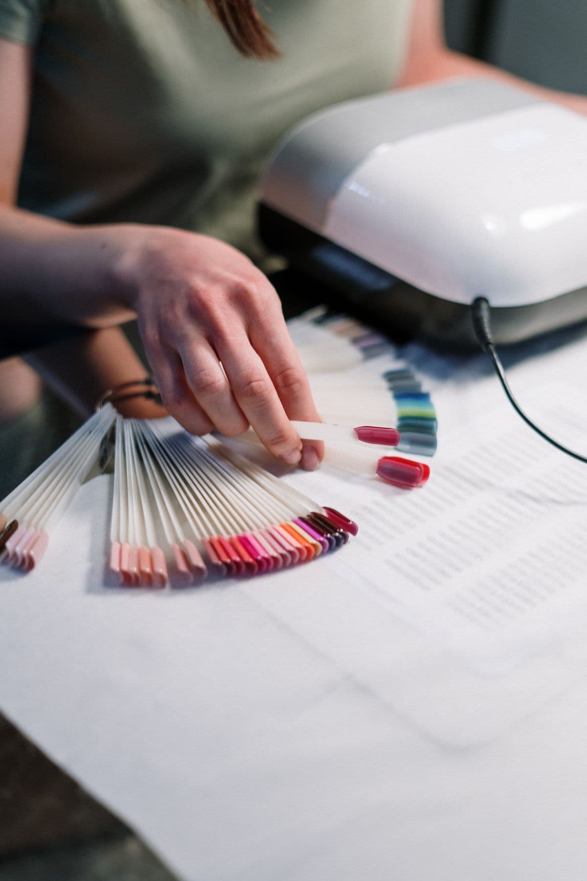 Una manicurista mostrando el muestrario de tips con decenas de colores de esmalte.